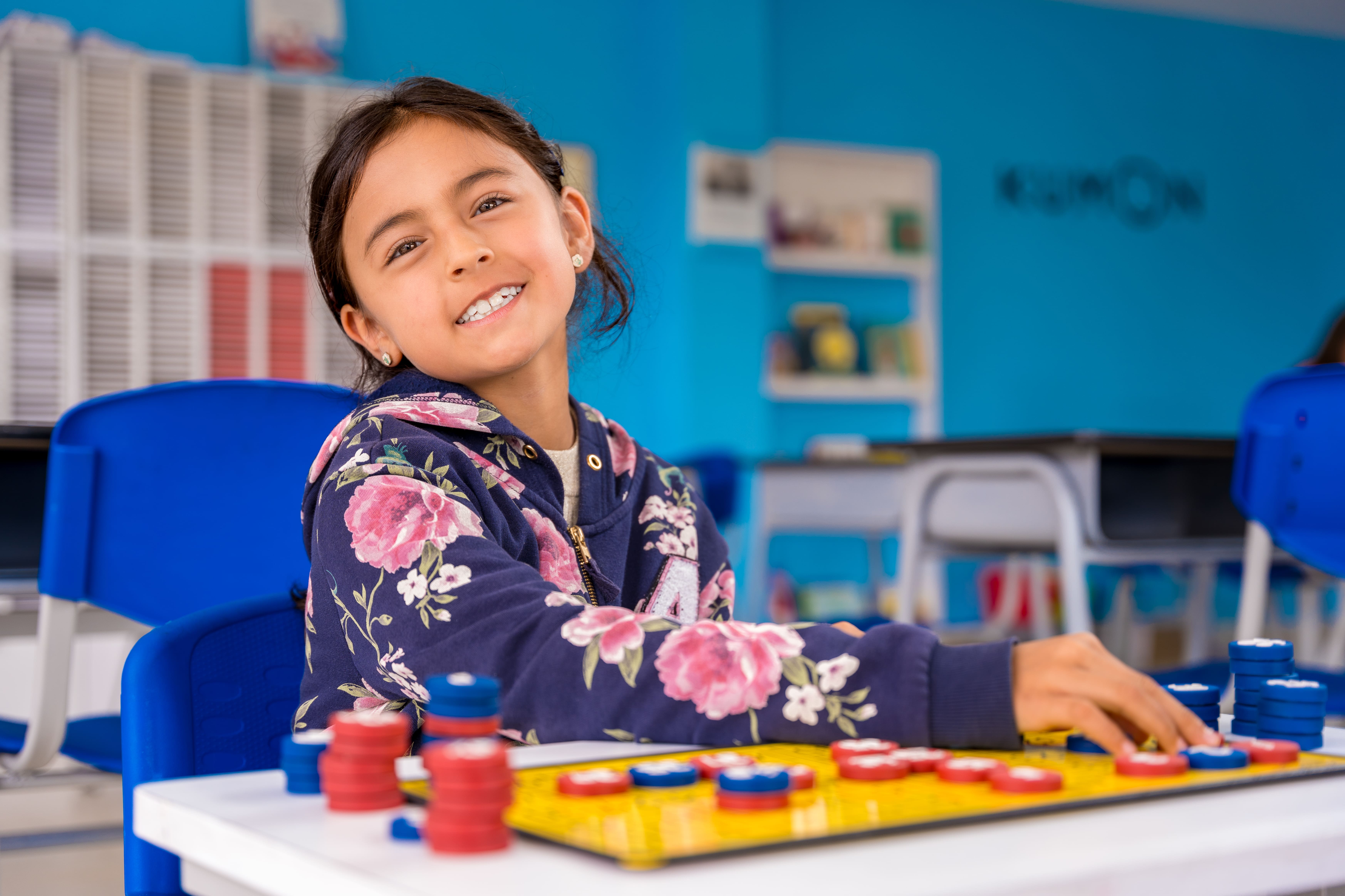 Niña estudiando matemáticas básicas con tablero magnético en un centro Kumon, disfrutando del aprendizaje-Uruguay