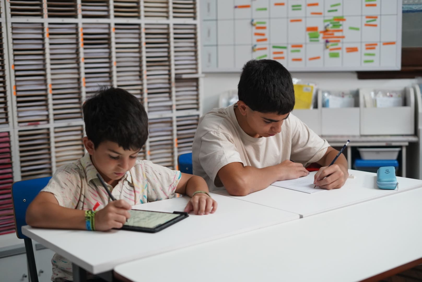 Alumnos haciendo la tarea en el material didáctico, la tablet y el cuadernillo-Uruguay