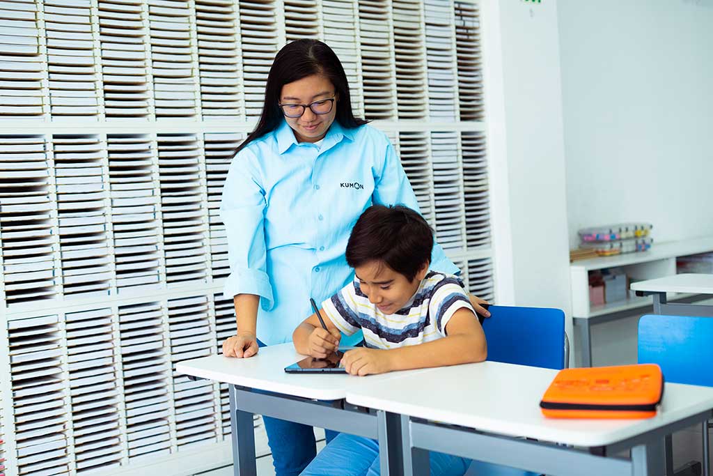 Alumno trabajando con enfoque y concentración en su rutina de aprendizaje individualizado, mientras la orientadora lo observa.